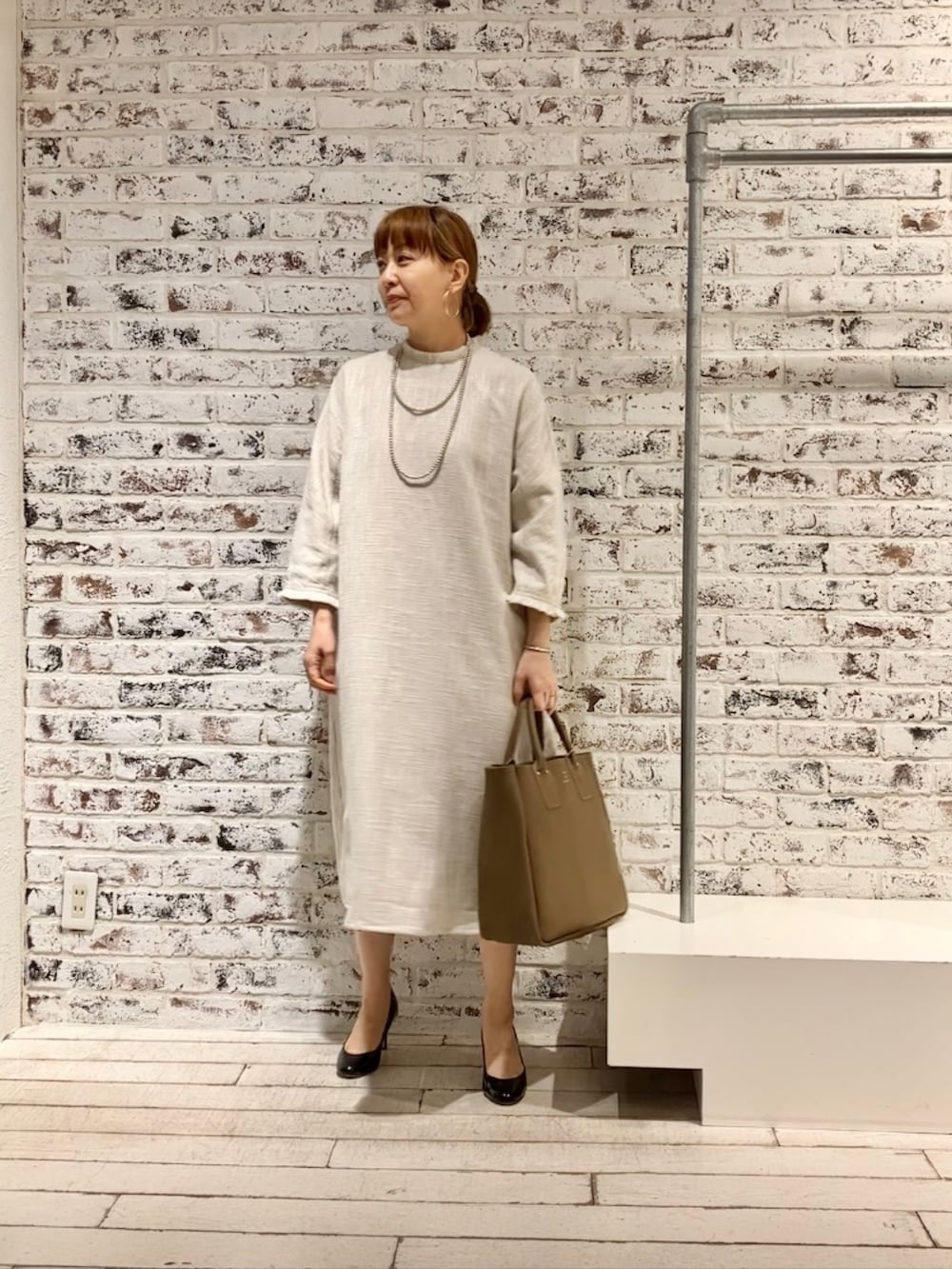 ホワイト系のワンピース、ベージュ系のショルダーバッグを着用したレディースの春コーディネートの2枚目の写真