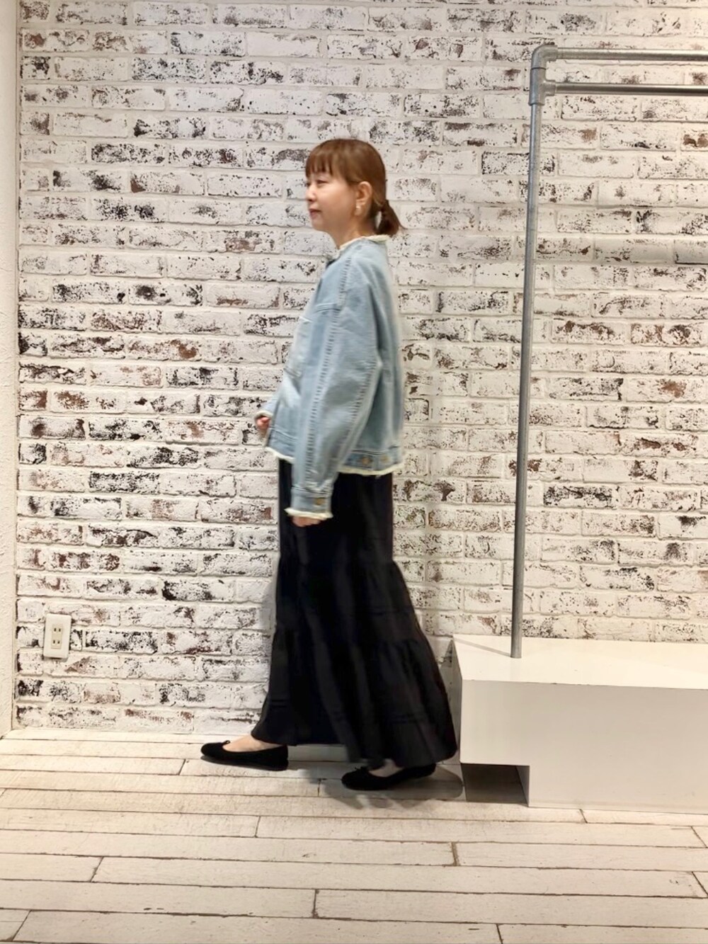 ブルー系のデニムジャケット、ブラック系のスカートを着用したレディースの春コーディネートの3枚目の写真