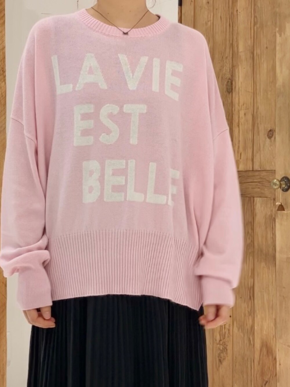 ピンク系のニット/セーター、ブラック系のスカートを着用したレディースの秋コーディネートの4枚目の写真