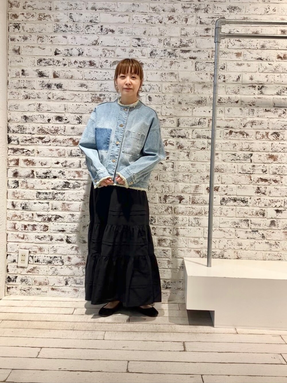 ブルー系のデニムジャケット、ブラック系のスカートを着用したレディースの春コーディネートの5枚目の写真