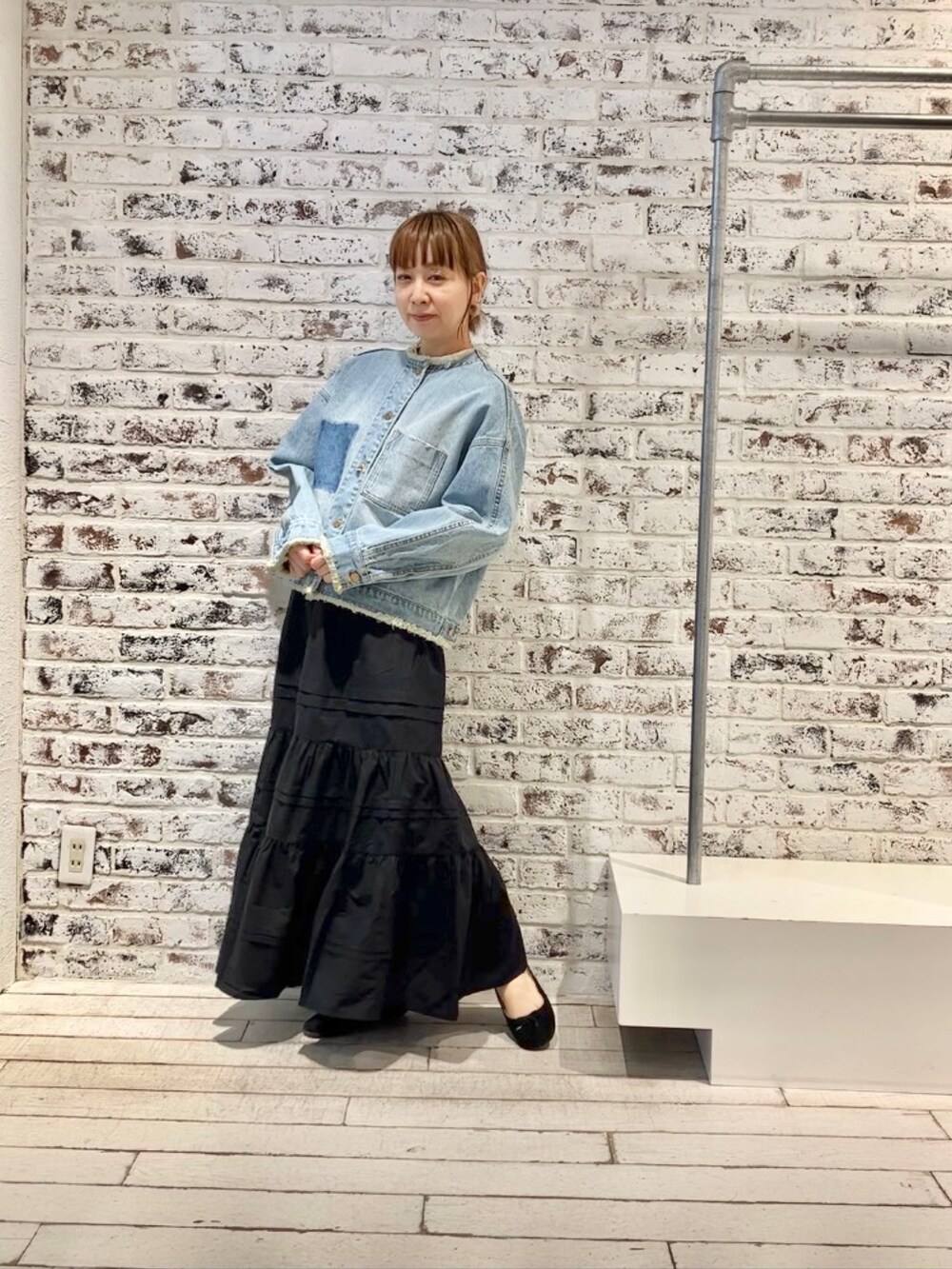 ブルー系のデニムジャケット、ブラック系のスカートを着用したレディースの春コーディネートの2枚目の写真