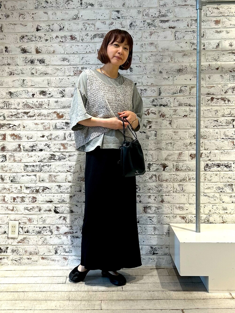 ホワイト系のベスト、ブラック系のスカート、グレー系のTシャツ/カットソーを着用したレディースの夏コーディネートの4枚目の写真