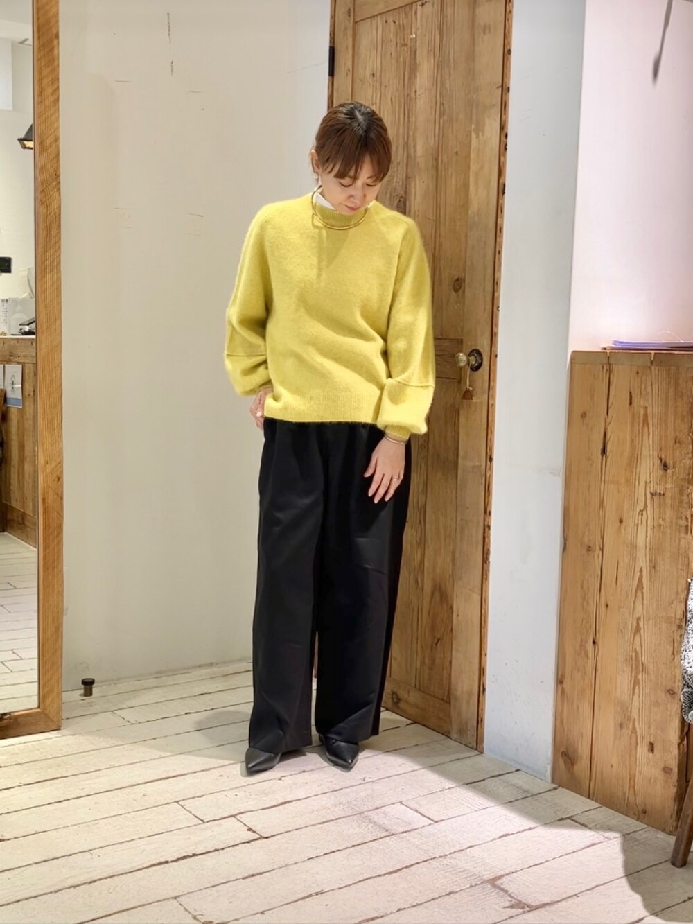 イエロー系のニット/セーター、ブラック系のスラックスを着用したレディースの秋コーディネートの3枚目の写真