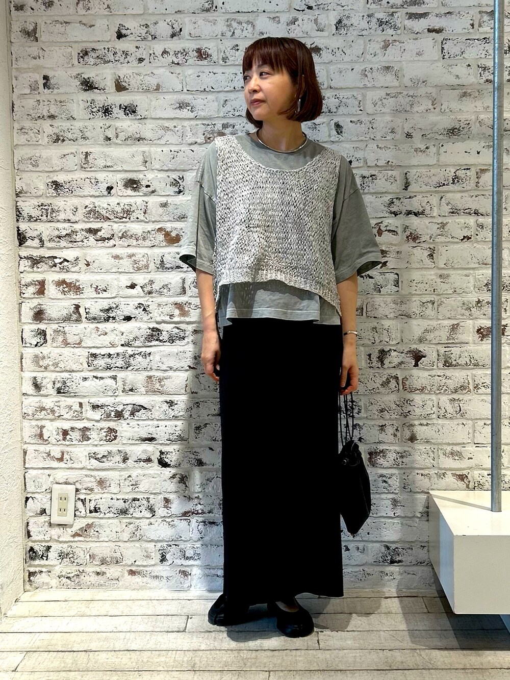 ホワイト系のベスト、ブラック系のスカート、グレー系のTシャツ/カットソーを着用したレディースの夏コーディネートの2枚目の写真