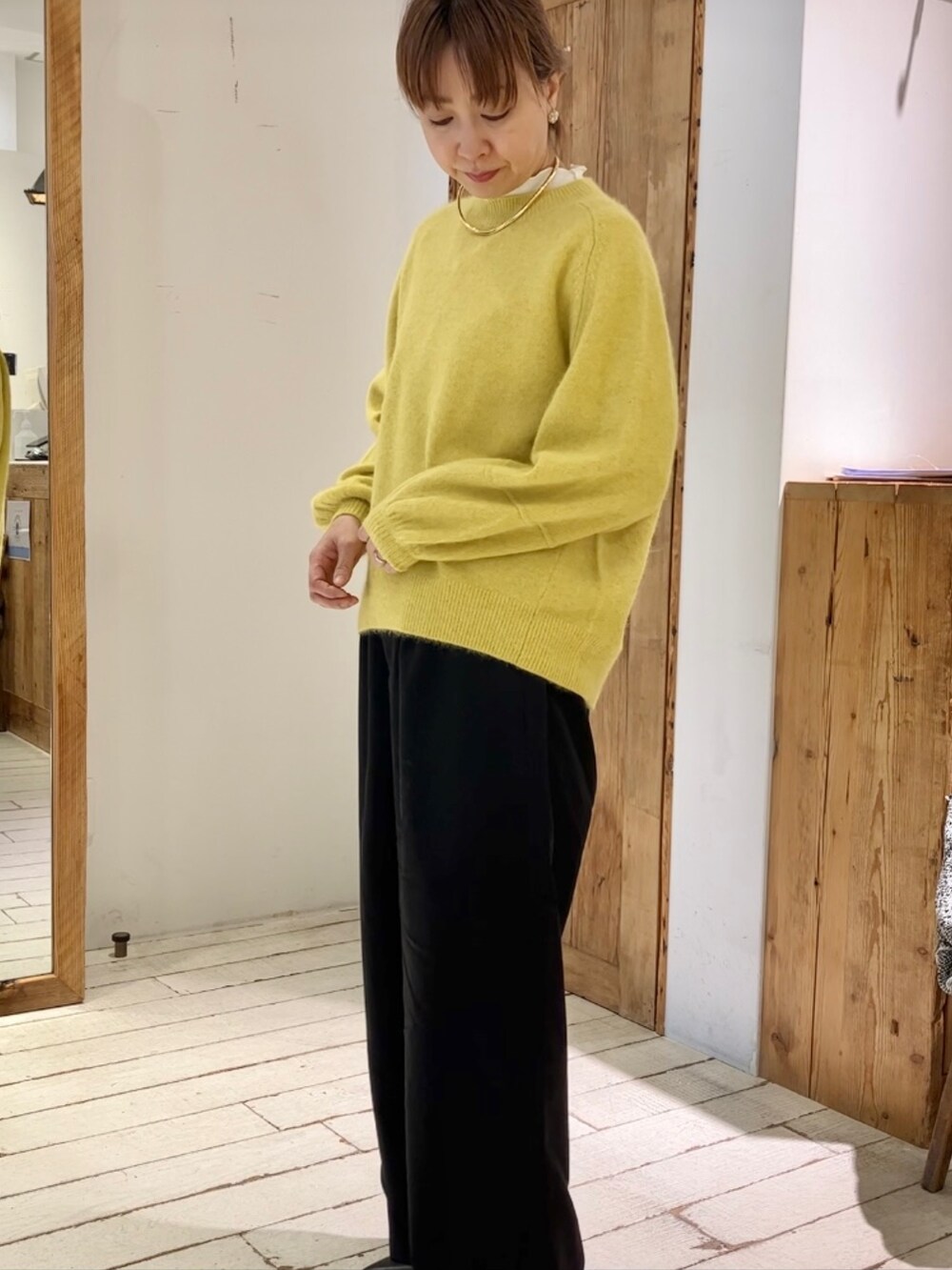 イエロー系のニット/セーター、ブラック系のスラックスを着用したレディースの秋コーディネートの4枚目の写真