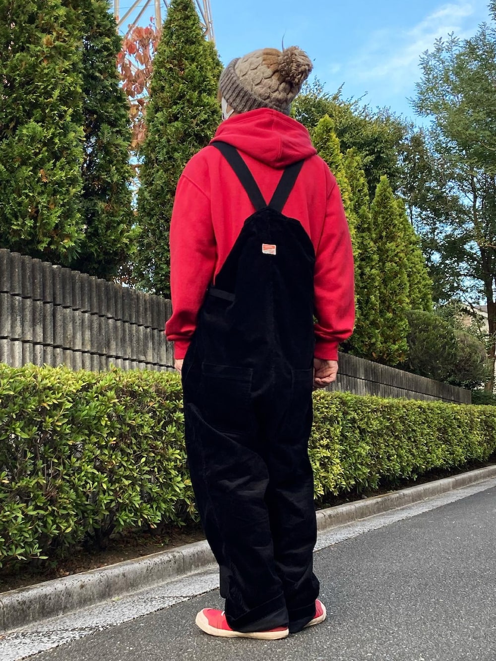 レッド系のスニーカー、ブラック系のサロペット/オーバーオール、レッド系のパーカーを着用したメンズの秋コーディネートの2枚目の写真