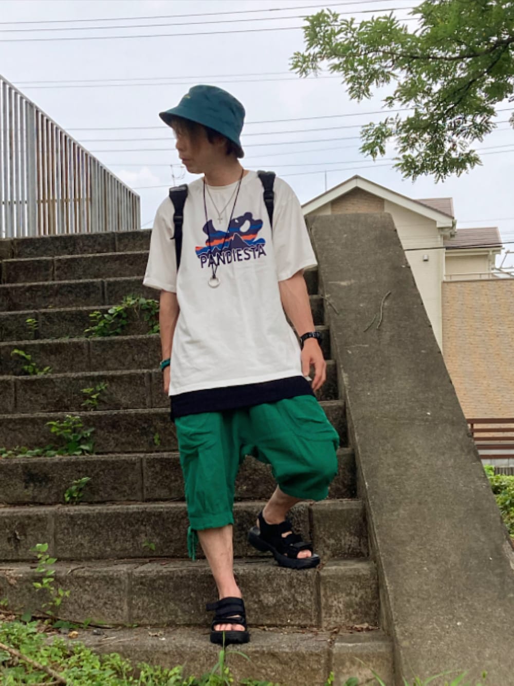 ブラック系のサンダル、グリーン系のその他パンツ、ホワイト系のTシャツ/カットソーを着用したメンズの夏コーディネートの3枚目の写真