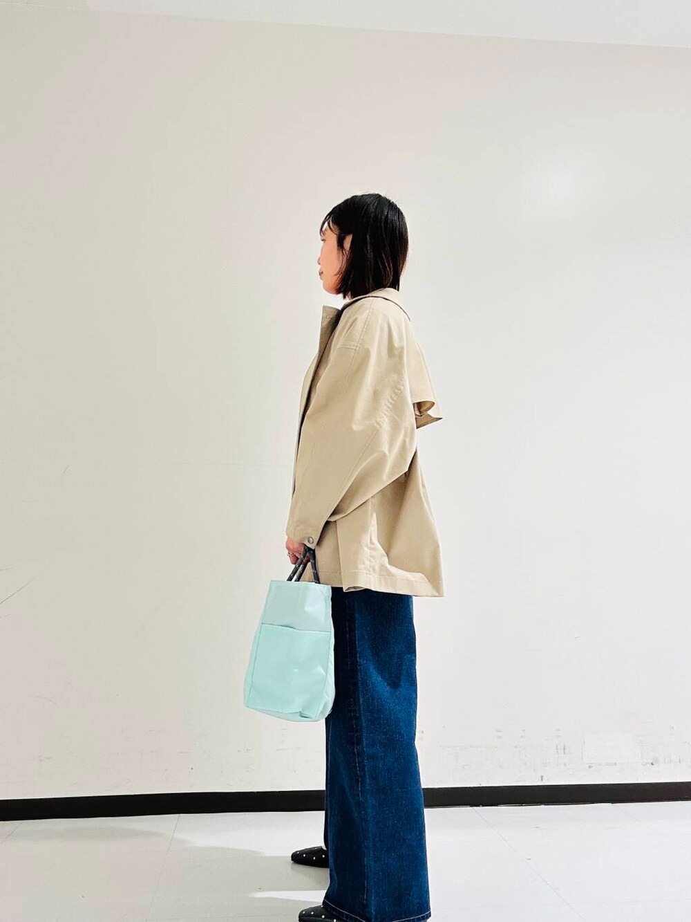 ベージュ系のトレンチコート、ブラック系のパンプス、レッド系のニット/セーターを着用したレディースの春コーディネートの2枚目の写真