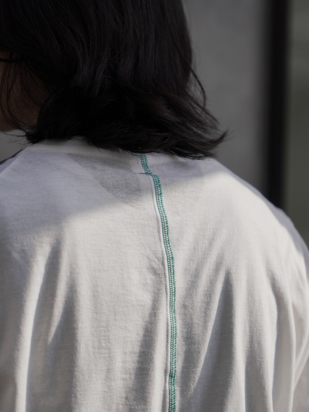 ホワイト系のTシャツ/カットソー、グレー系のスラックス、ブラック系のシューズを着用したメンズの夏コーディネートの3枚目の写真