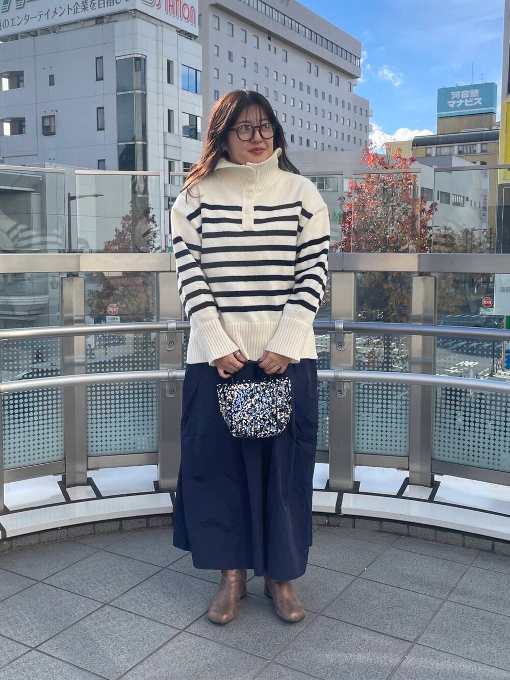 シルバー系のショルダーバッグ、ブルー系のスカート、ブラウン系のブーツを着用したレディースの冬コーディネートの2枚目の写真