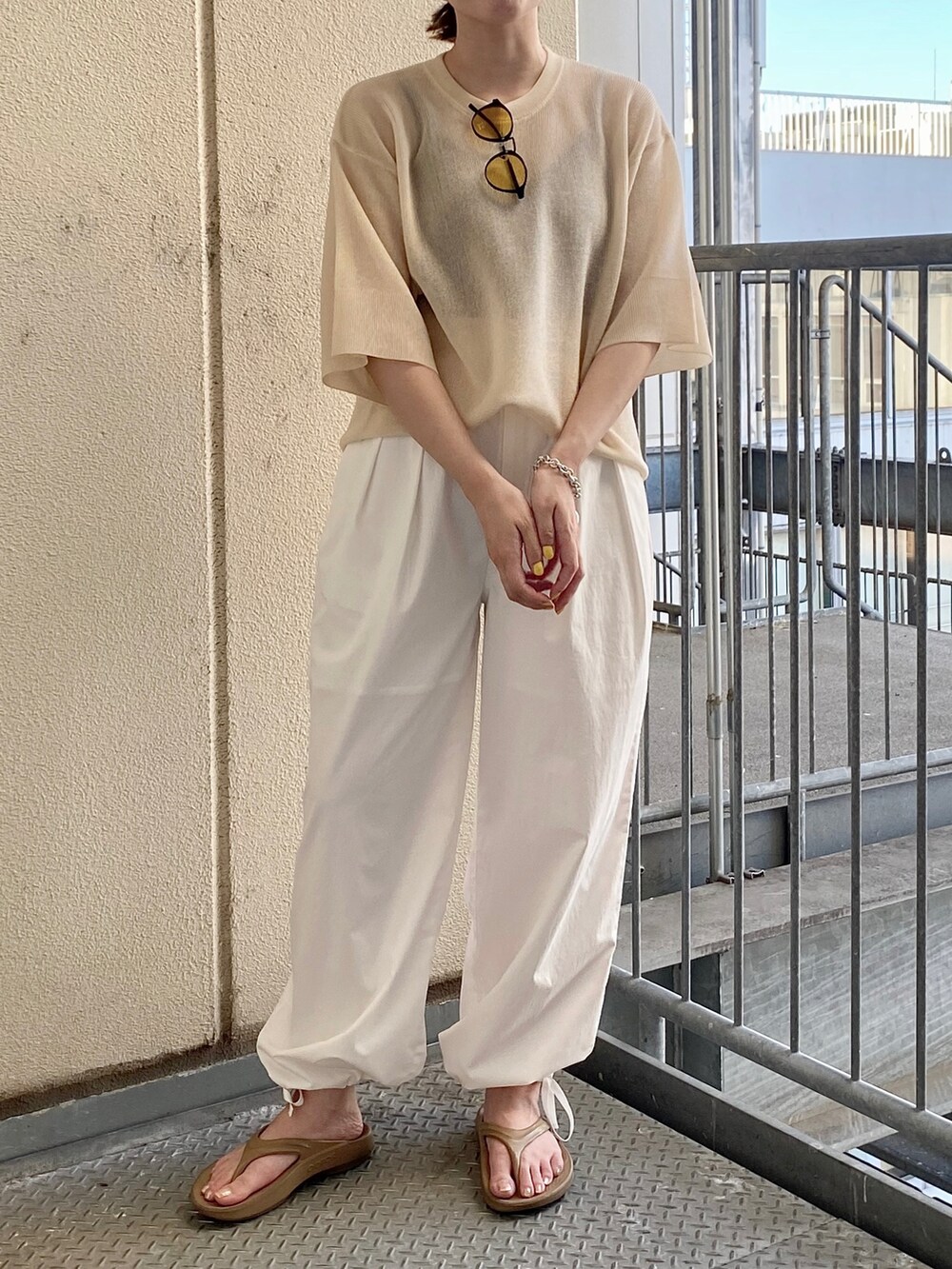 ベージュ系のニット/セーター、ホワイト系のその他パンツ、イエロー系のサングラスを着用したレディースの夏コーディネートの2枚目の写真