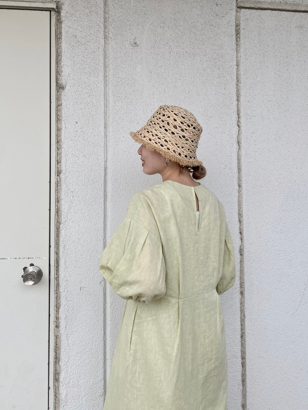 グリーン系のワンピース、ホワイト系のサンダル、ベージュ系のハットを着用したレディースの夏コーディネートの2枚目の写真