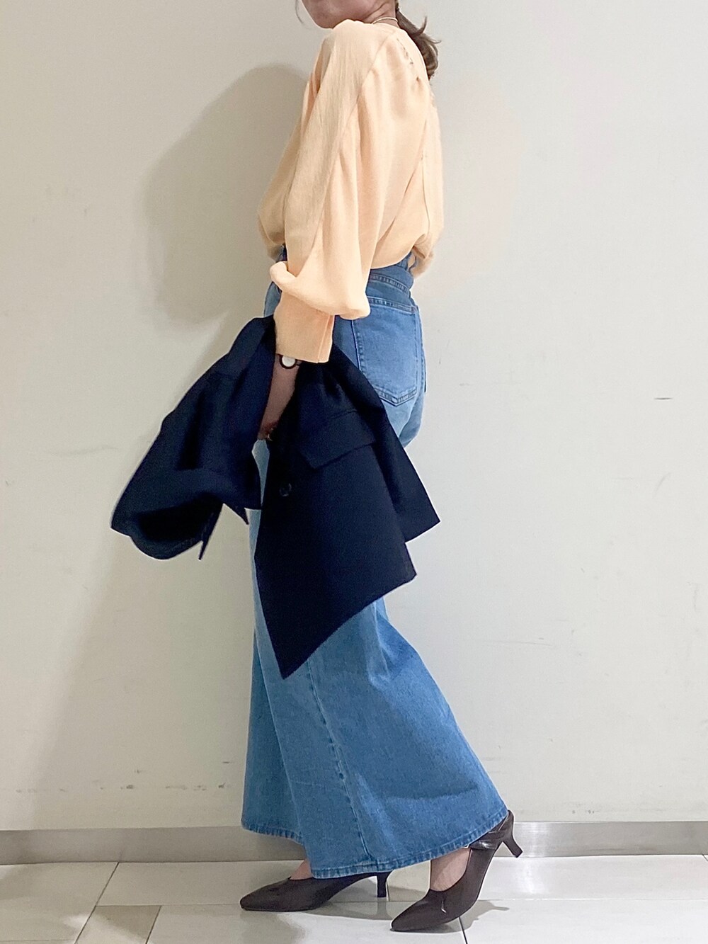 オレンジ系のシャツ/ブラウス、ブルー系のデニムパンツ、ブラウン系のパンプスを着用したレディースの春コーディネートの2枚目の写真