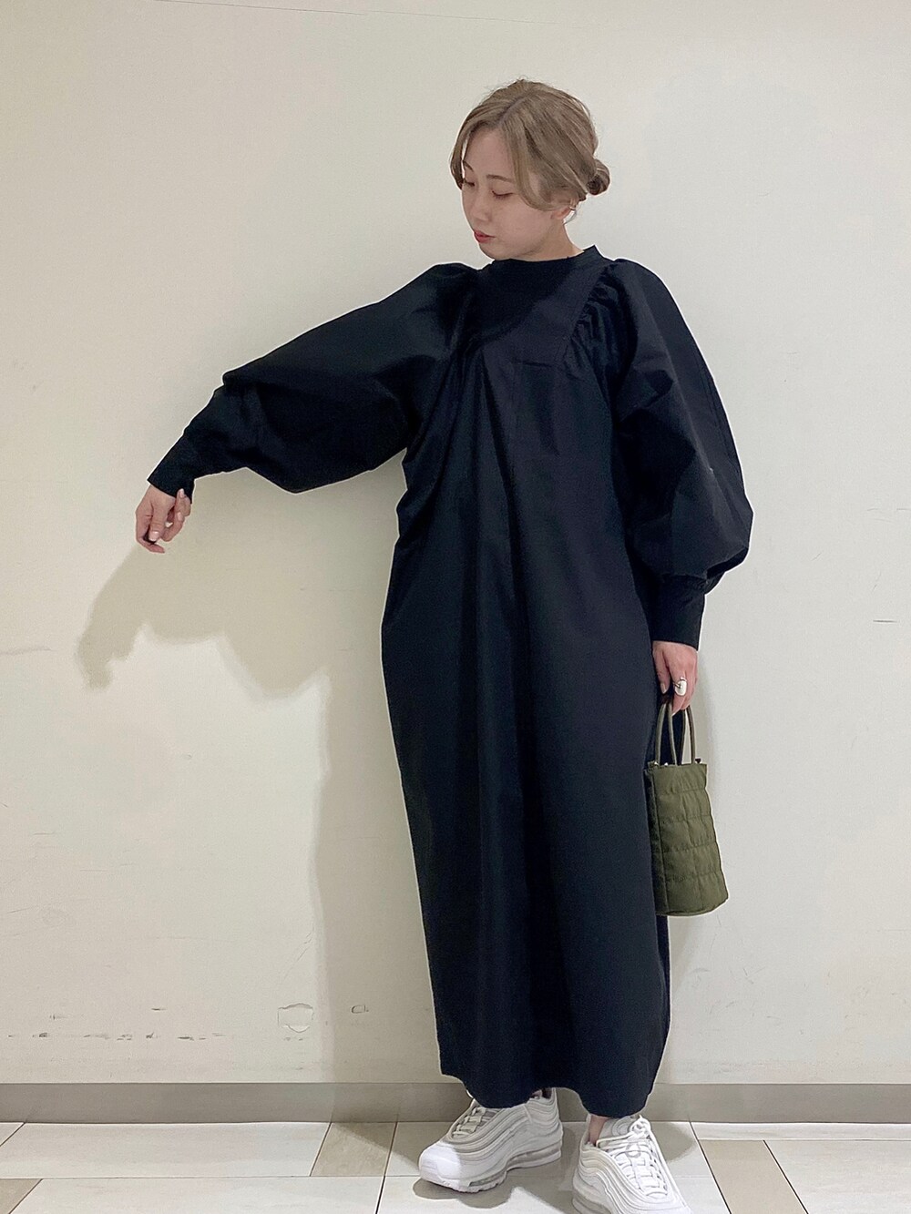 ブラック系のワンピース、グリーン系のショルダーバッグを着用したレディースの冬コーディネートの2枚目の写真