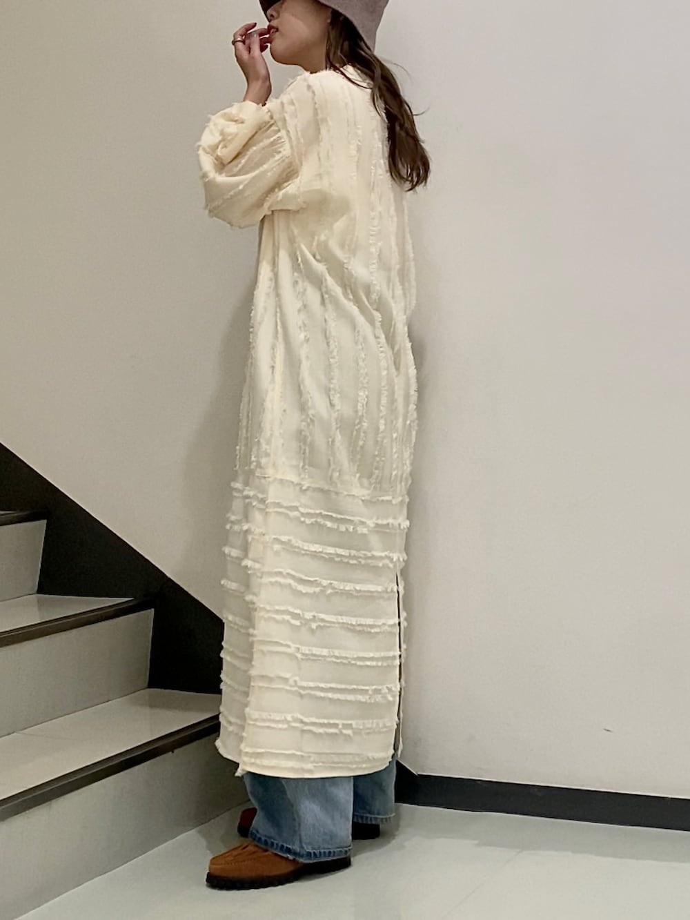 オレンジ系のハンドバッグ、ホワイト系のワンピース、ブラウン系のハットを着用したレディースの冬コーディネートの2枚目の写真