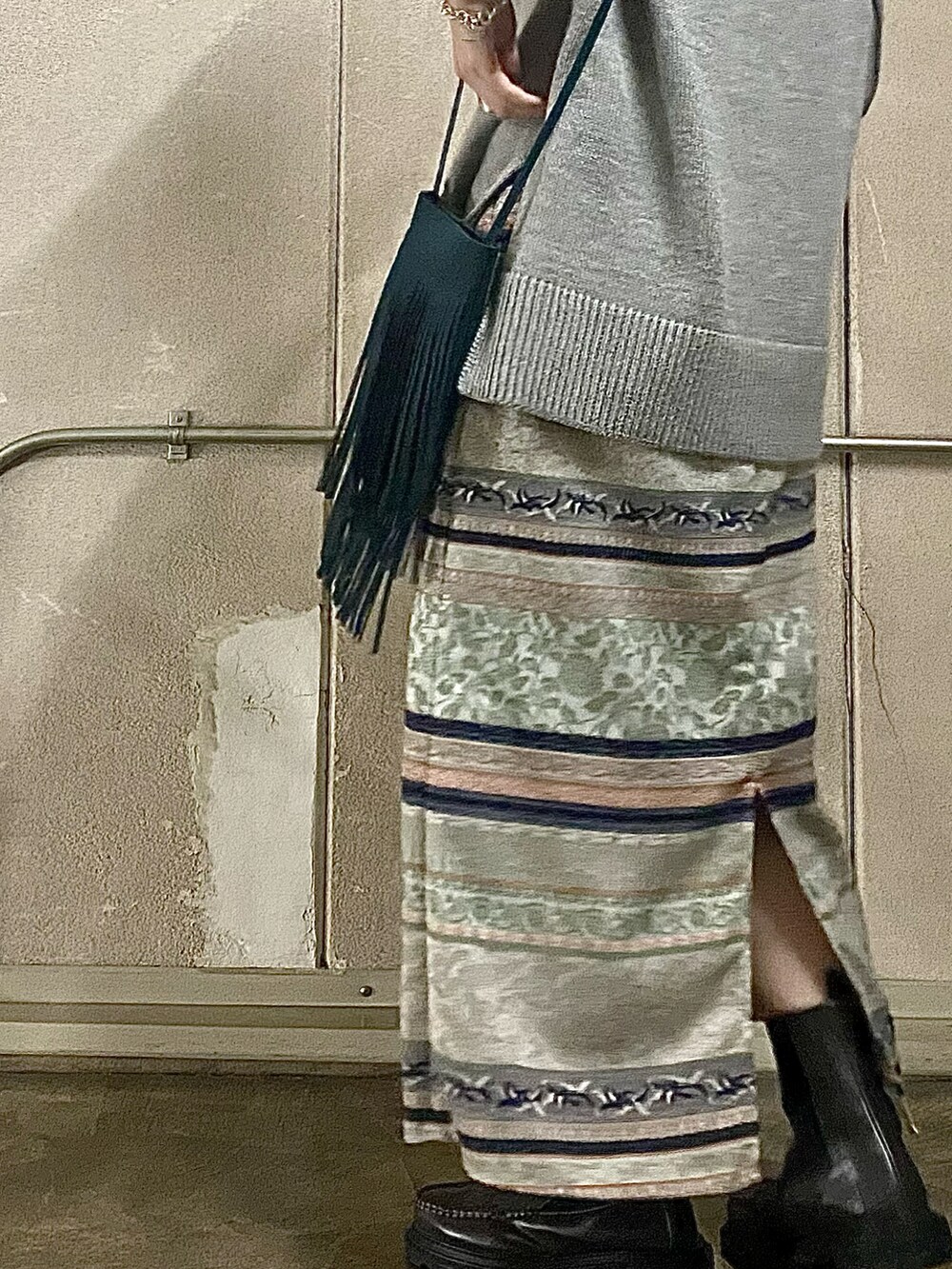 グレー系のニット/セーター、グリーン系のスカート、グリーン系のショルダーバッグを着用したレディースの冬コーディネートの2枚目の写真