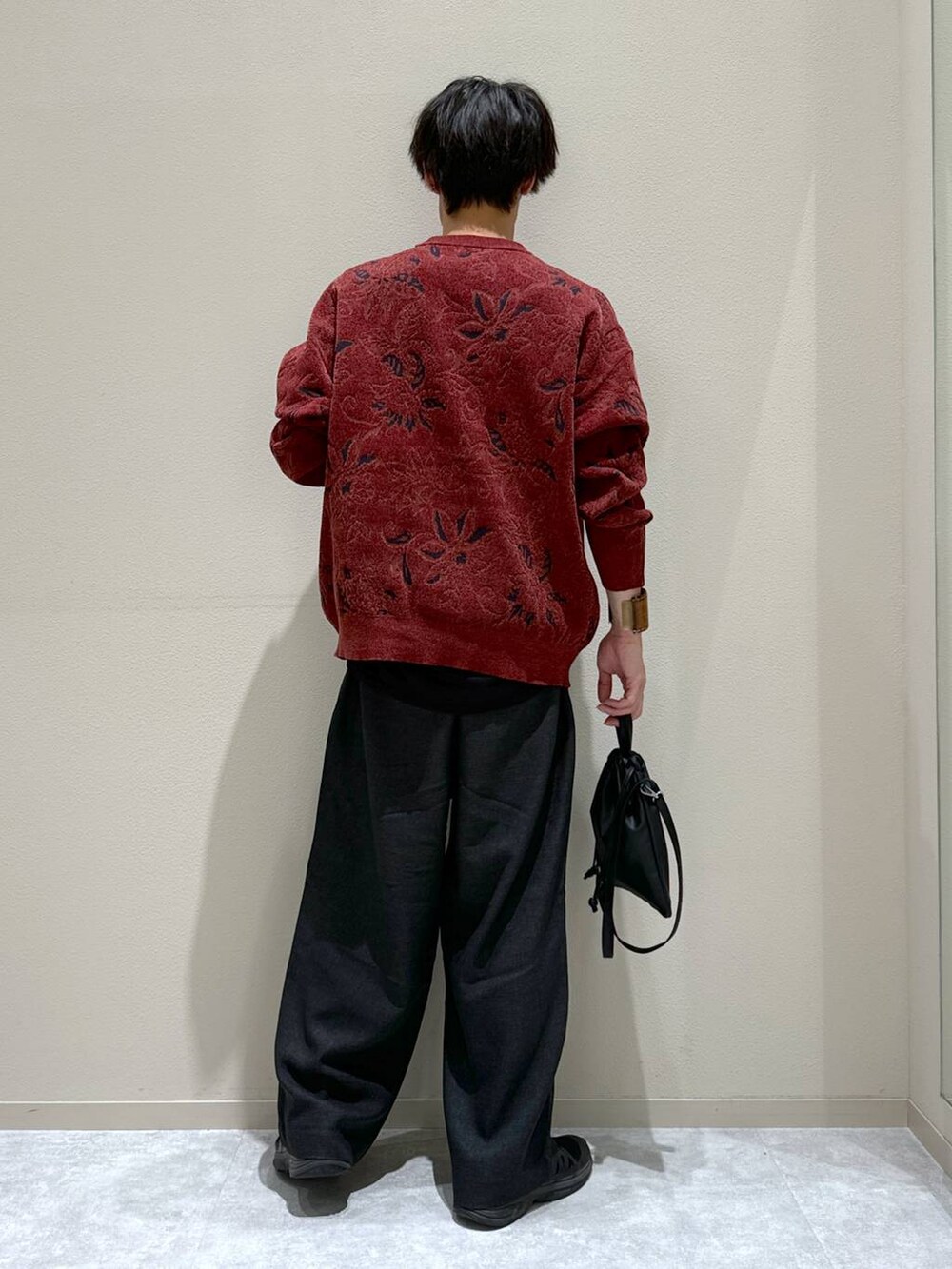 ブラック系のショルダーバッグ、レッド系のニット/セーター、グレー系のスラックスを着用したメンズの秋コーディネートの3枚目の写真