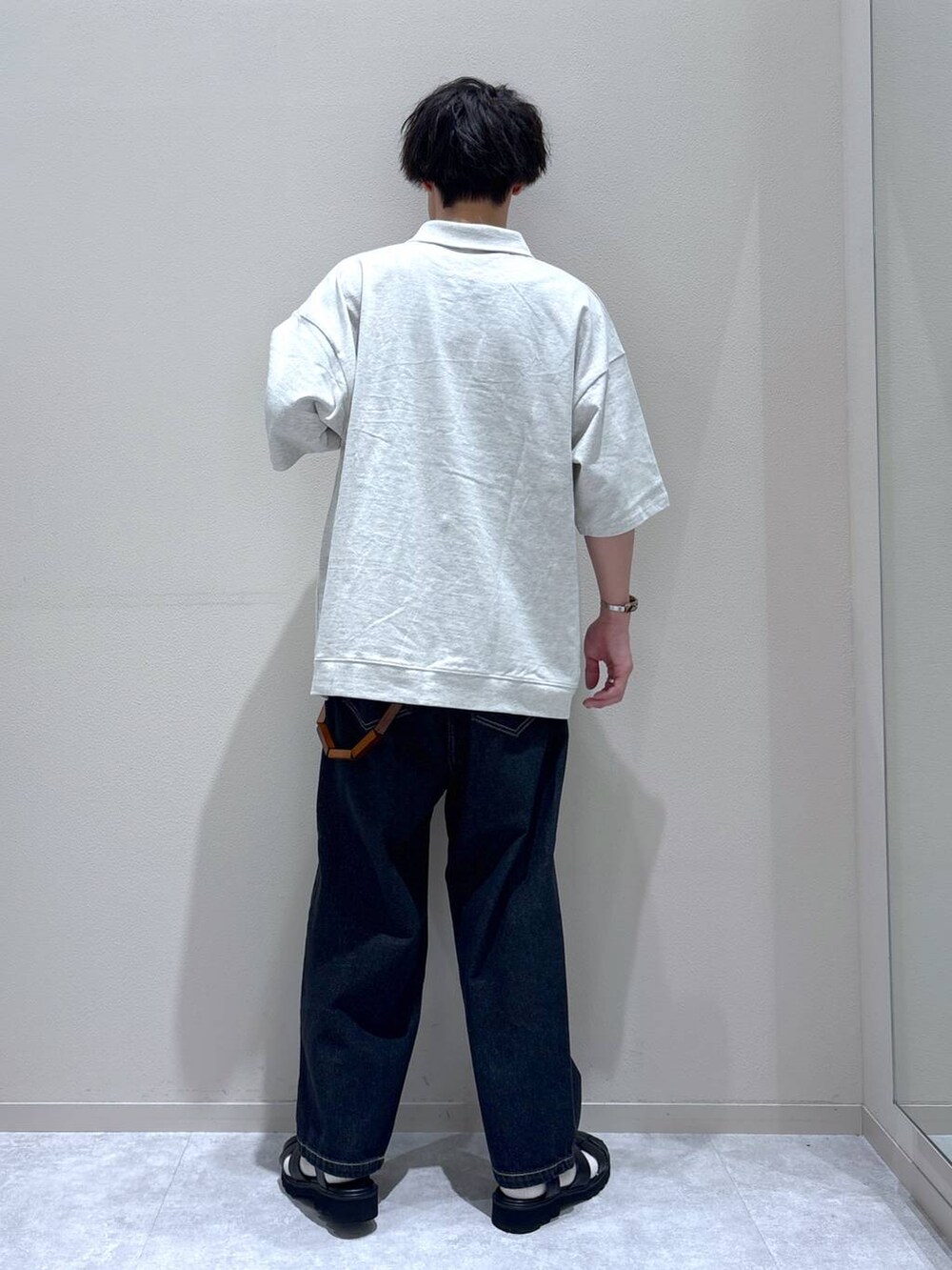 ブラック系のデニムパンツ、ブラック系のサンダル、ホワイト系のTシャツ/カットソーを着用したメンズの夏コーディネートの2枚目の写真