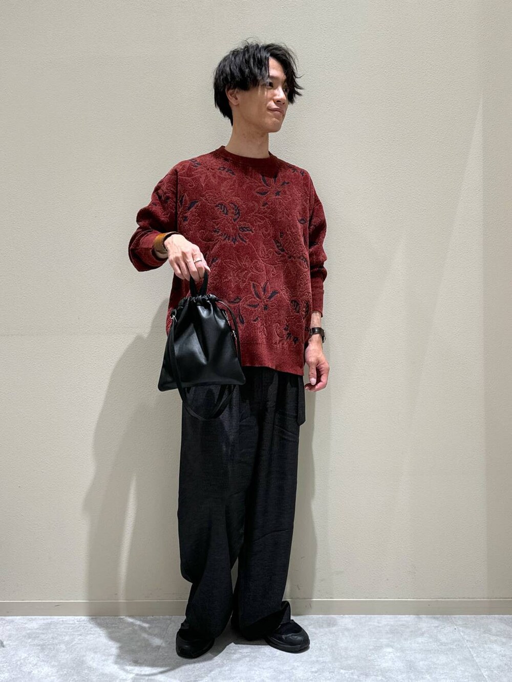 ブラック系のショルダーバッグ、レッド系のニット/セーター、グレー系のスラックスを着用したメンズの秋コーディネートの2枚目の写真