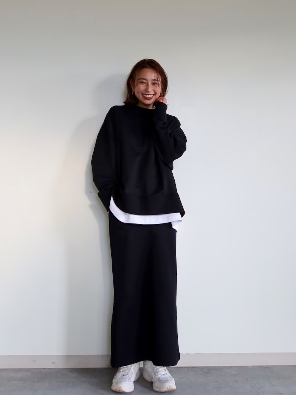 ブラック系のスウェット、ブラック系のスカート、ホワイト系のスニーカーを着用したレディースの冬コーディネートの4枚目の写真