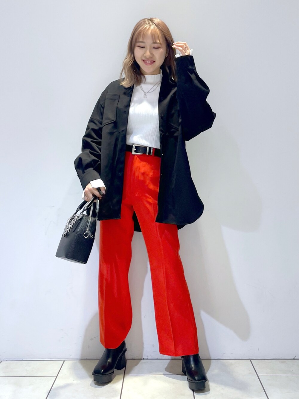 ホワイト系のニット/セーター、ブラック系のシャツ/ブラウス、レッド系のスラックスを着用したレディースの冬コーディネートの2枚目の写真