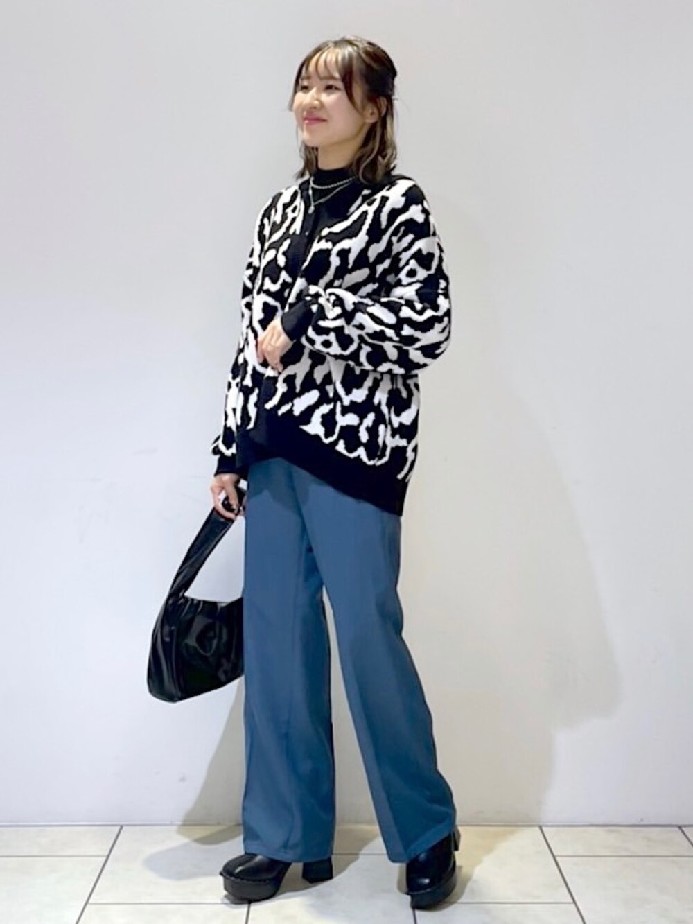 ブラック系のニット/セーター、ブラック系のニット/セーター、ブルー系のスラックスを着用したレディースの秋コーディネートの2枚目の写真