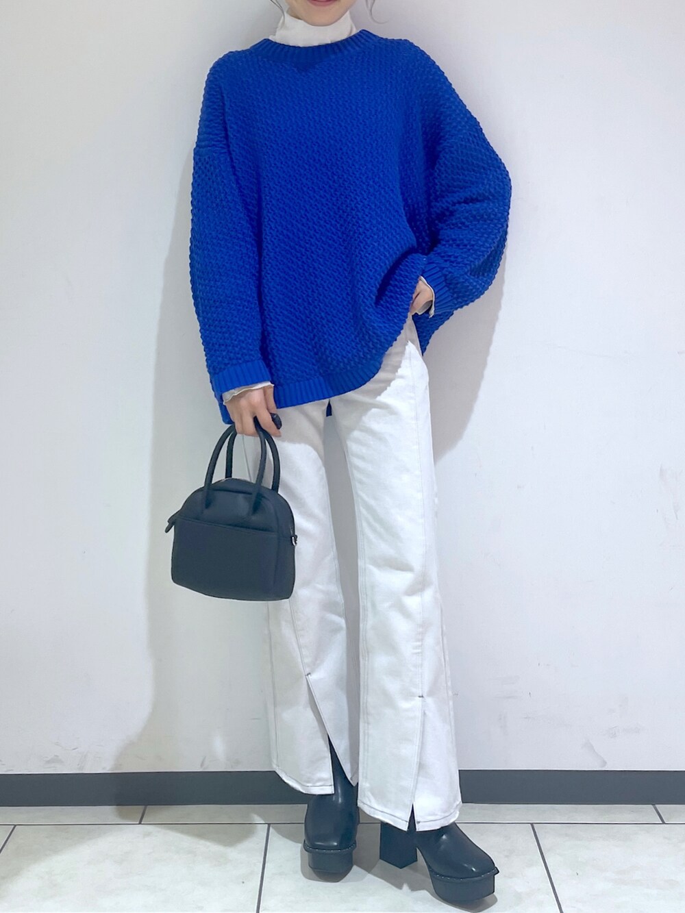 ホワイト系のTシャツ/カットソー、ブルー系のニット/セーター、ホワイト系のデニムパンツを着用したレディースの冬コーディネートの3枚目の写真