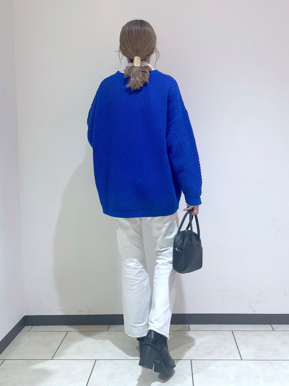 ホワイト系のTシャツ/カットソー、ブルー系のニット/セーター、ホワイト系のデニムパンツを着用したレディースの冬コーディネートの2枚目の写真