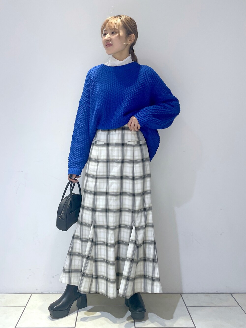ブルー系のニット/セーター、ホワイト系のTシャツ/カットソー、ホワイト系のスカートを着用したレディースの冬コーディネートの2枚目の写真