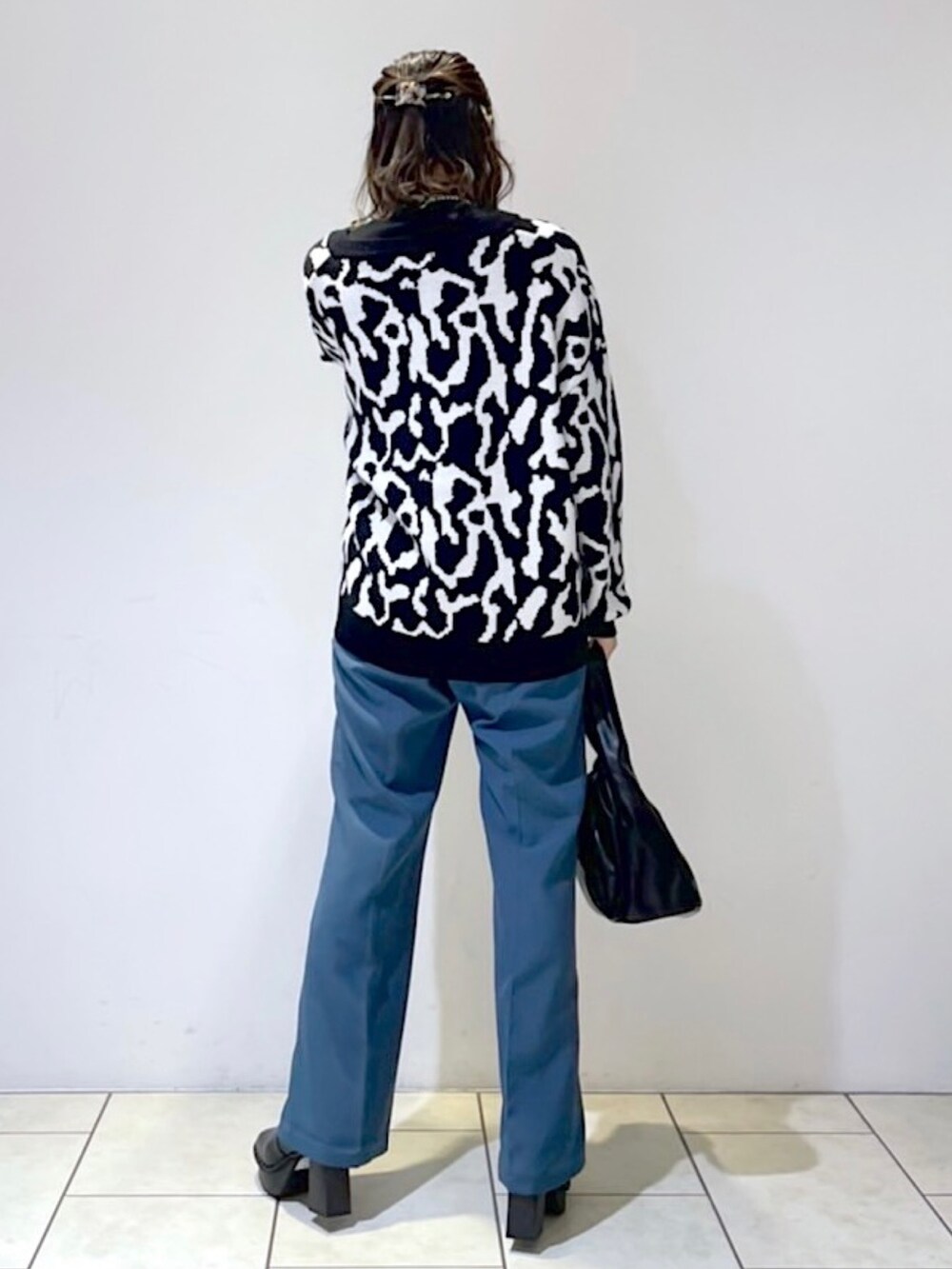 ブラック系のニット/セーター、ブラック系のニット/セーター、ブルー系のスラックスを着用したレディースの秋コーディネートの3枚目の写真