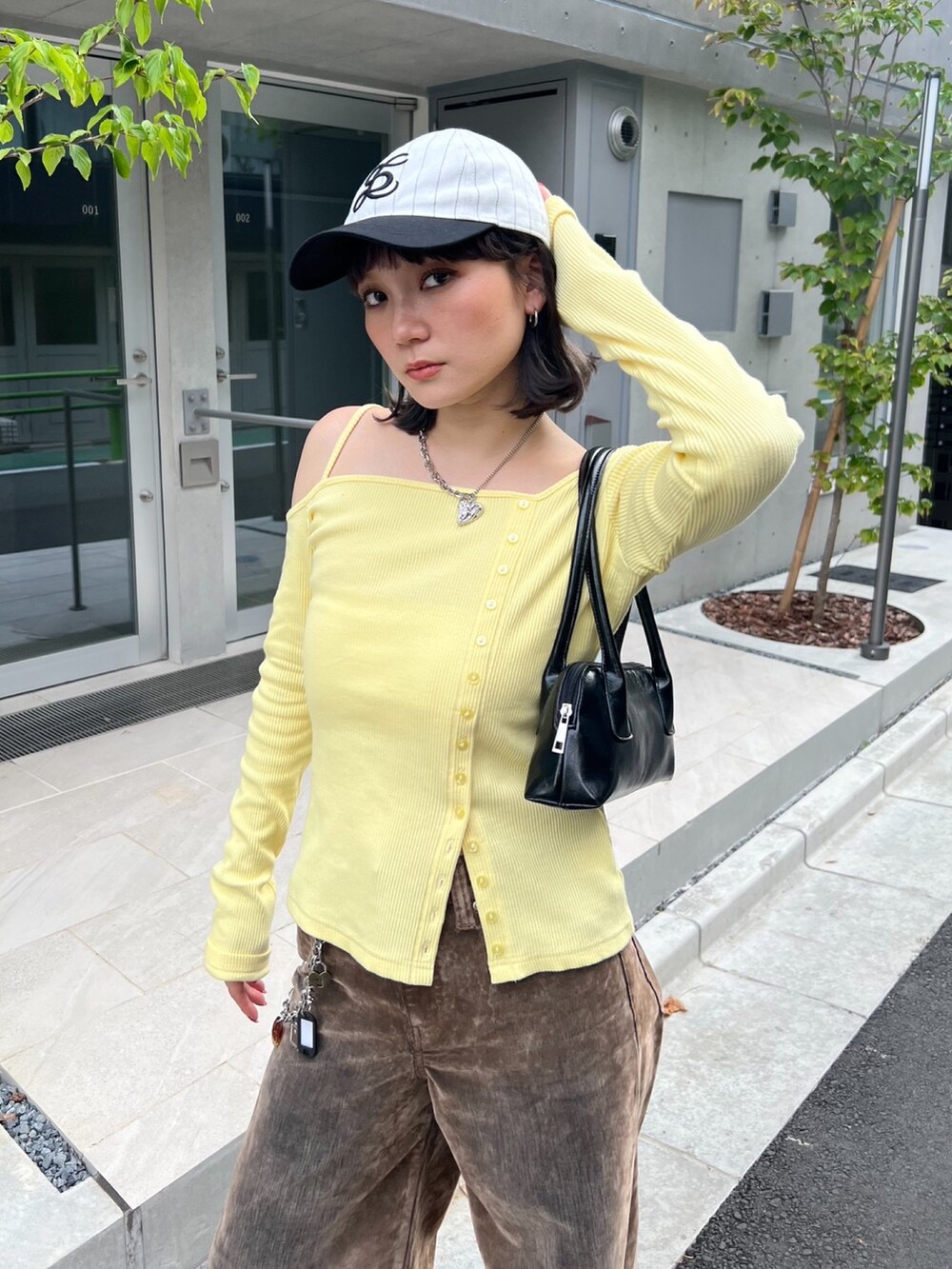 イエロー系のTシャツ/カットソー、ブラウン系のデニムパンツ、シルバー系のチャームを着用したレディースの秋コーディネートの2枚目の写真