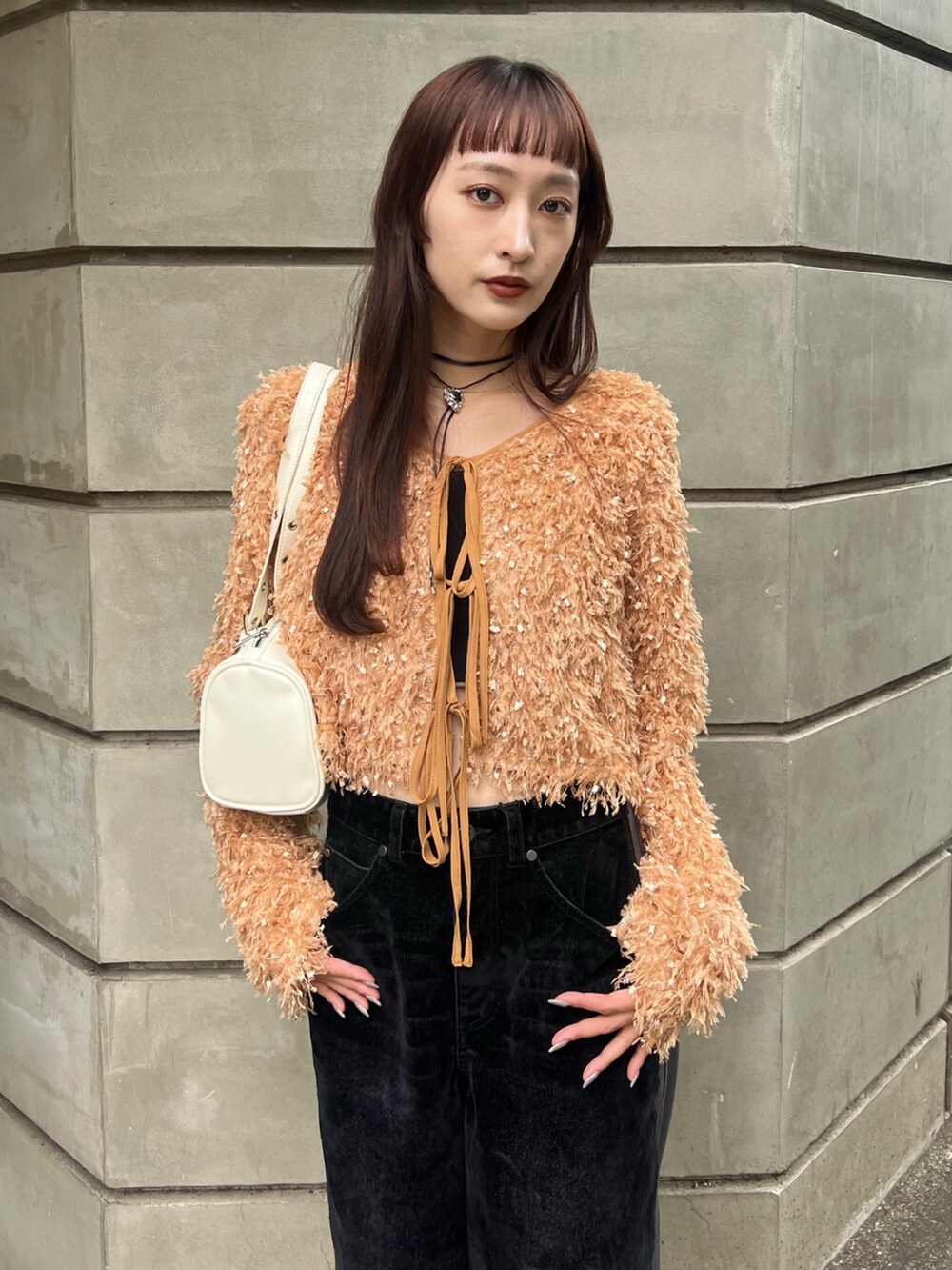 ブラック系のデニムパンツ、ホワイト系のショルダーバッグ、ベージュ系のカーディガン/ボレロを着用したレディースの冬コーディネートの4枚目の写真