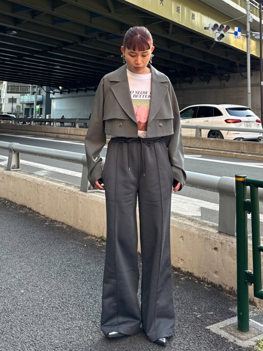 グレー系のトレンチコート、ホワイト系のTシャツ/カットソー、ブラック系のスラックスを着用したレディースの冬コーディネートの2枚目の写真