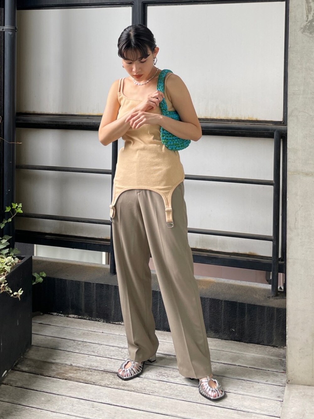 シルバー系のサンダル、グリーン系のハンドバッグ、オレンジ系のキャミソールを着用したレディースの夏コーディネートの3枚目の写真