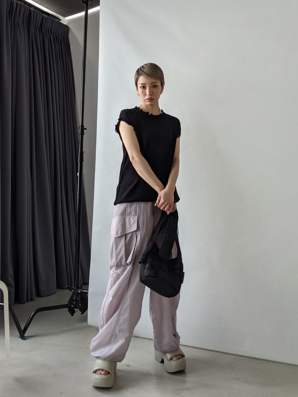 ブラック系のショルダーバッグ、ブラック系のニット/セーター、パープル系のスラックスを着用したレディースの春コーディネートの4枚目の写真