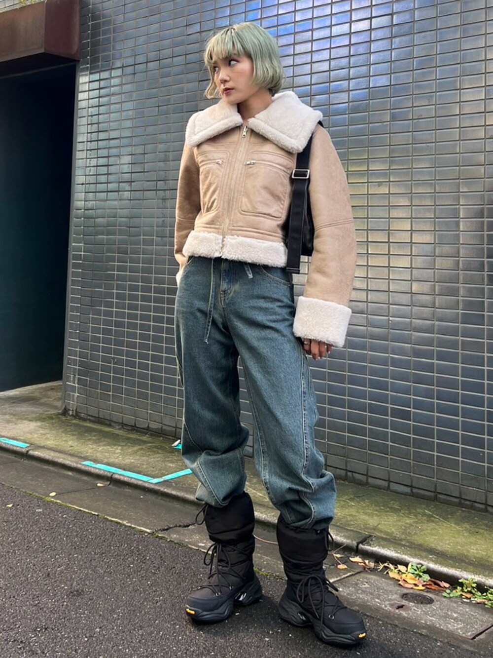 ブルー系のデニムパンツ、ブラック系のブーツ、ベージュ系のブルゾンを着用したレディースの秋コーディネートの2枚目の写真