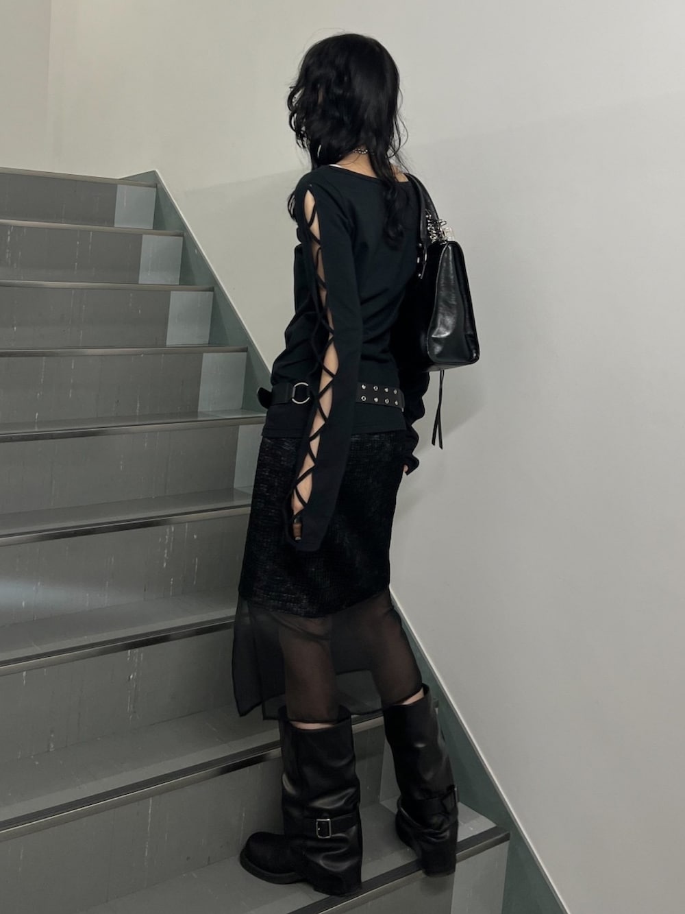 ブラック系のスカート、ブラック系のTシャツ/カットソー、ブラック系のブーツを着用したレディースの冬コーディネートの2枚目の写真