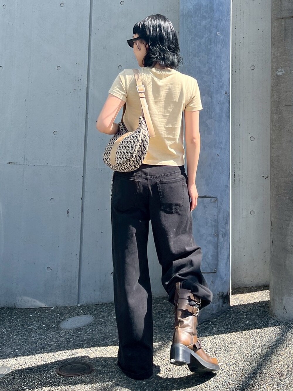 ベージュ系のTシャツ/カットソー、ベージュ系のハンドバッグ、ブラック系のデニムパンツを着用したレディースの春コーディネートの2枚目の写真