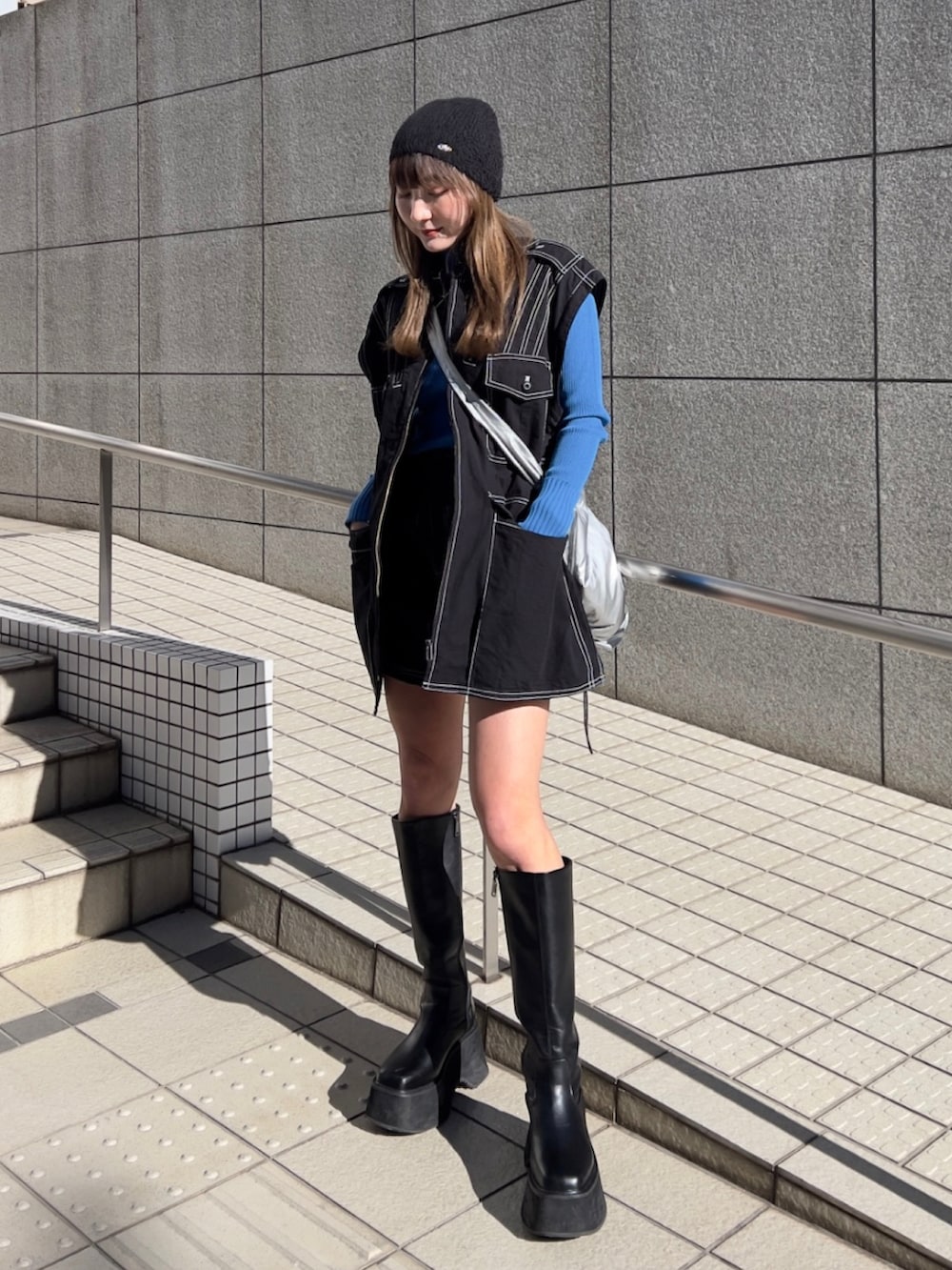 ブラック系のミリタリージャケット、ブラック系のスカート、ブラック系のブーツを着用したレディースの冬コーディネートの2枚目の写真