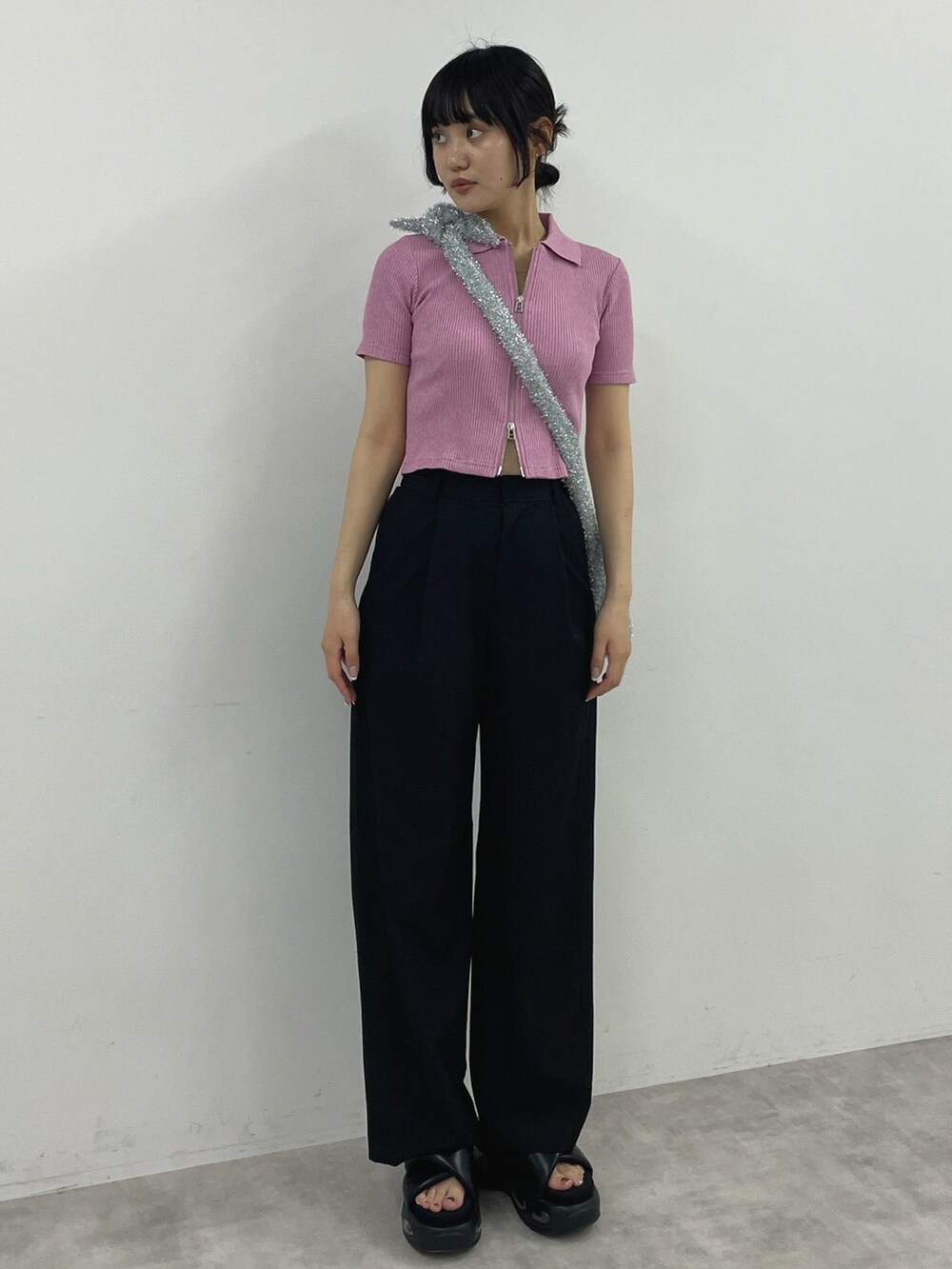 ピンク系のTシャツ/カットソー、ブラック系のスラックス、シルバー系のショルダーバッグを着用したレディースの春コーディネートの2枚目の写真