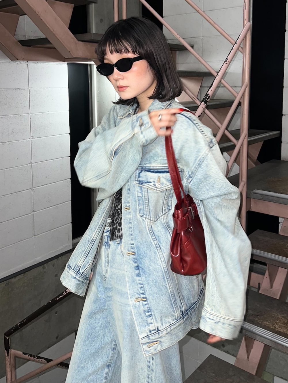 ブルー系のデニムジャケット、ブラック系のカーディガン/ボレロ、レッド系のショルダーバッグを着用したレディースの秋コーディネートの2枚目の写真