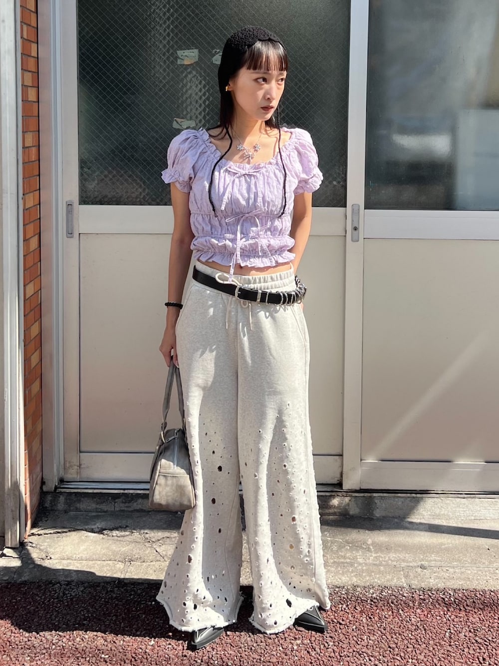 グレー系のハンドバッグ、グレー系のスウェットパンツ、パープル系のシャツ/ブラウスを着用したレディースの夏コーディネートの2枚目の写真