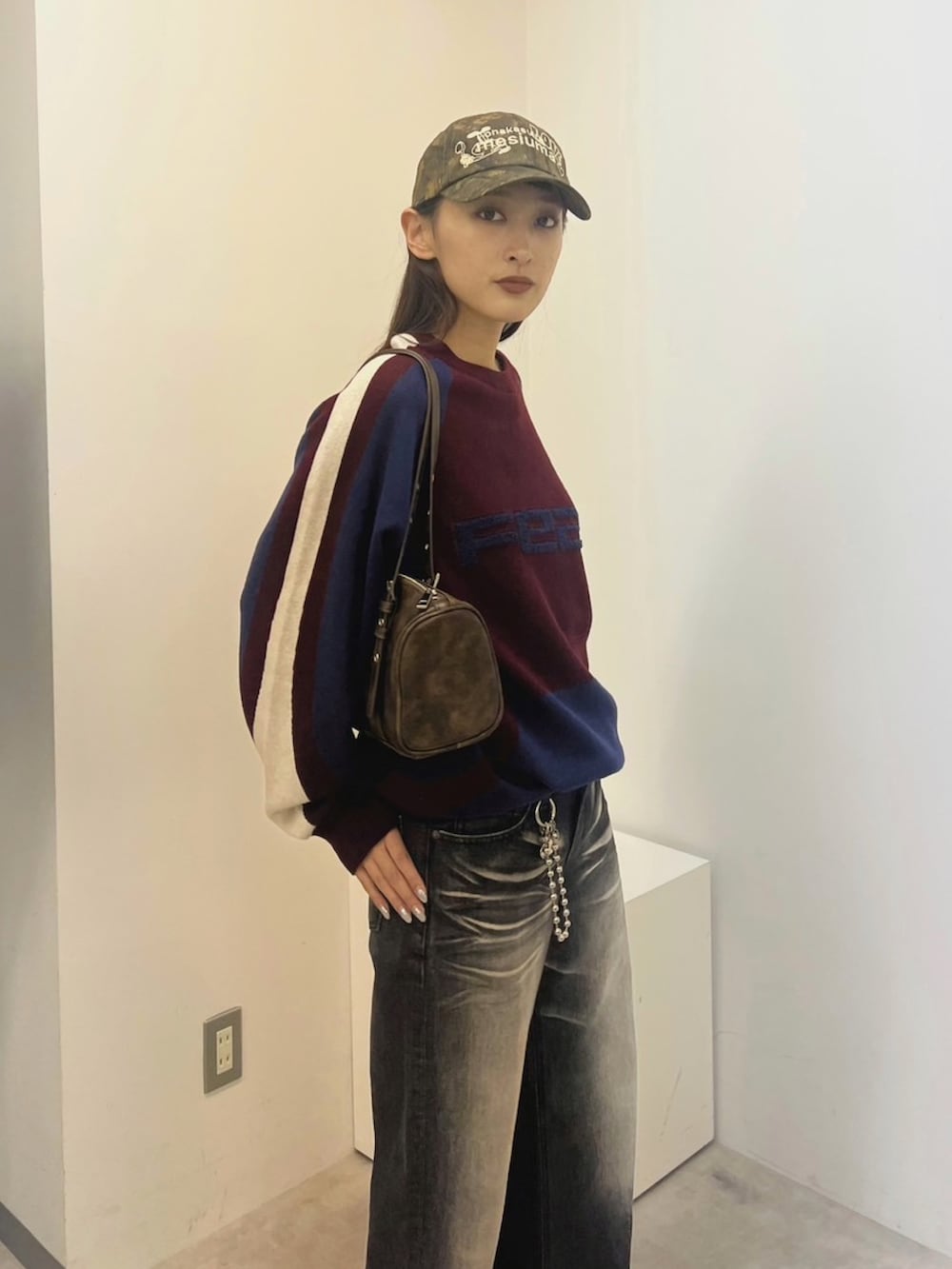ブラック系のデニムパンツ、ブラウン系のショルダーバッグ、レッド系のニット/セーターを着用したレディースの冬コーディネートの3枚目の写真