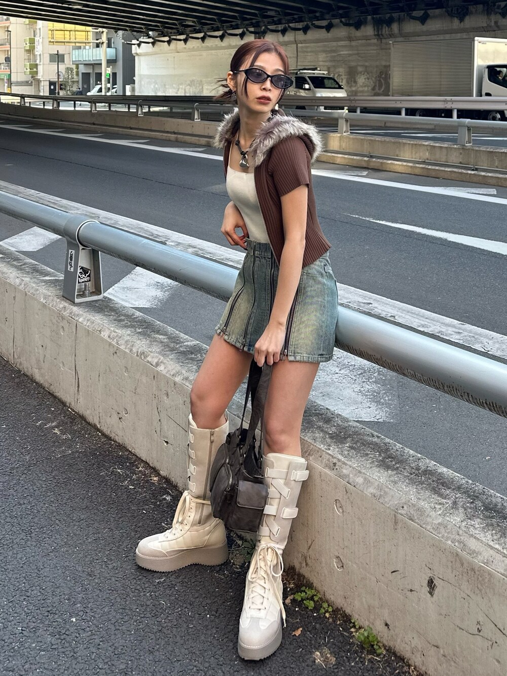 ブルー系のデニムスカート、ブラウン系のニット/セーター、ブラウン系のハンドバッグを着用したレディースの春コーディネートの3枚目の写真