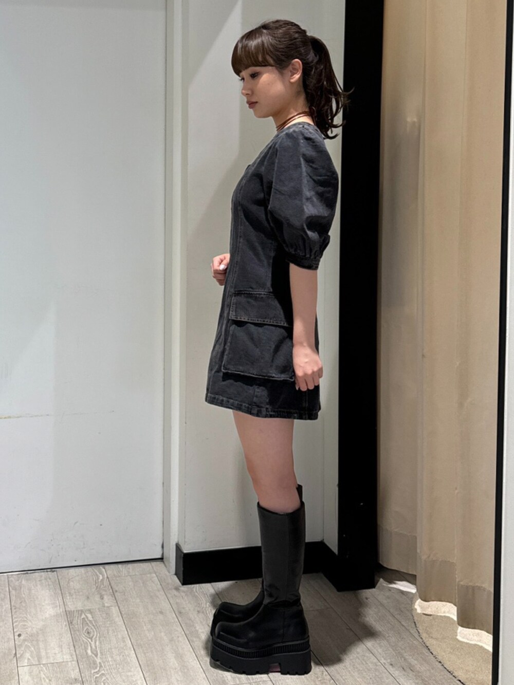 ブラック系のワンピース、ブラック系のブーツ、シルバー系のネックレスを着用したレディースの春コーディネートの2枚目の写真