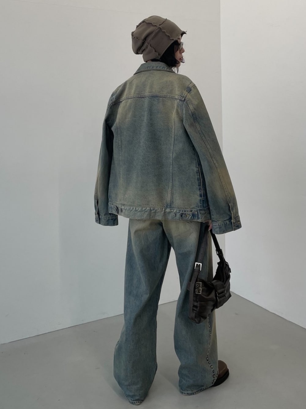 ブラウン系のハンドバッグ、ブルー系のデニムパンツ、ホワイト系のニット/セーターを着用したレディースの冬コーディネートの2枚目の写真