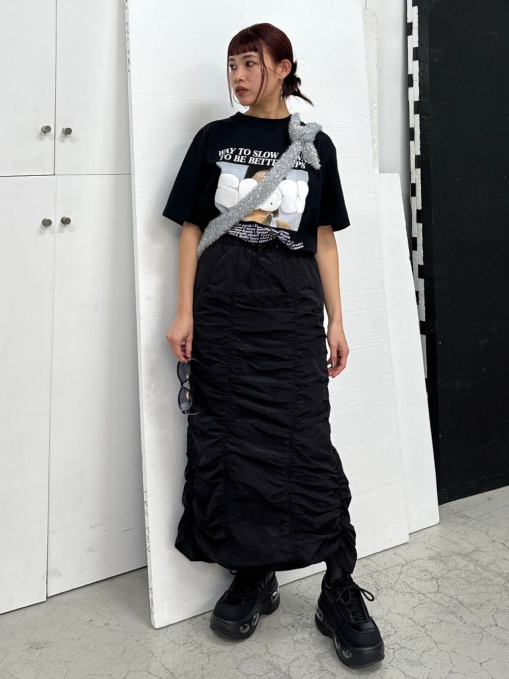 ブラック系のTシャツ/カットソー、ブラック系のスカート、ブラック系のスニーカーを着用したレディースの春コーディネートの2枚目の写真