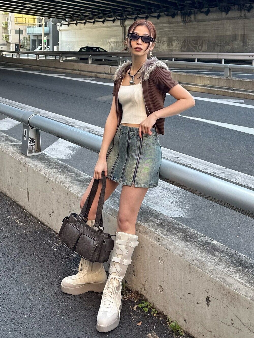 ブルー系のデニムスカート、ブラウン系のニット/セーター、ブラウン系のハンドバッグを着用したレディースの春コーディネートの2枚目の写真