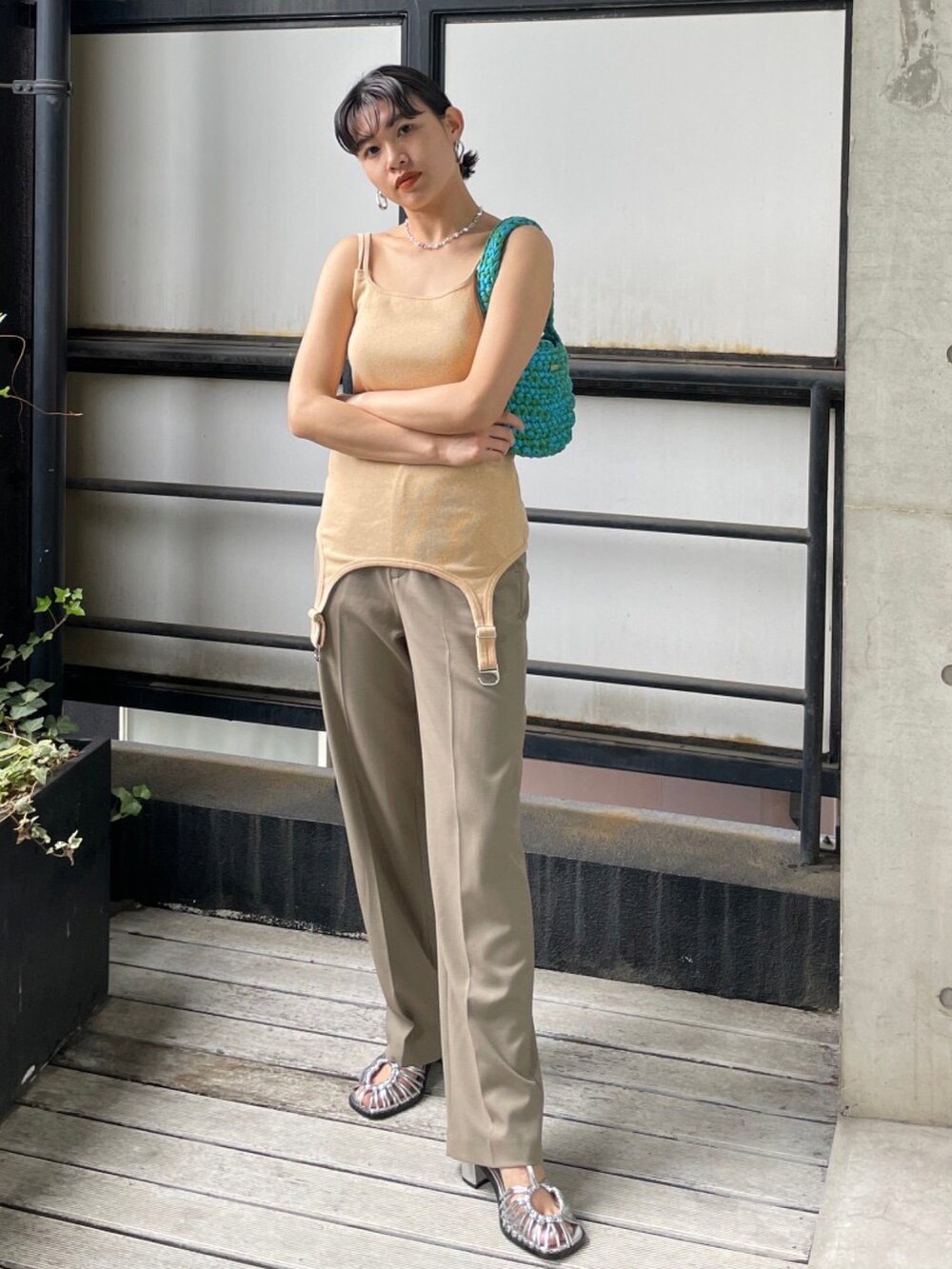 シルバー系のサンダル、グリーン系のハンドバッグ、オレンジ系のキャミソールを着用したレディースの夏コーディネートの2枚目の写真