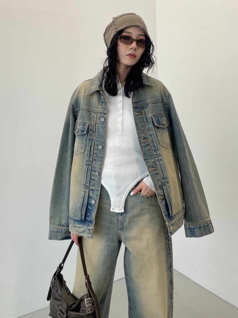 ブラウン系のハンドバッグ、ブルー系のデニムパンツ、ホワイト系のニット/セーターを着用したレディースの冬コーディネートの3枚目の写真